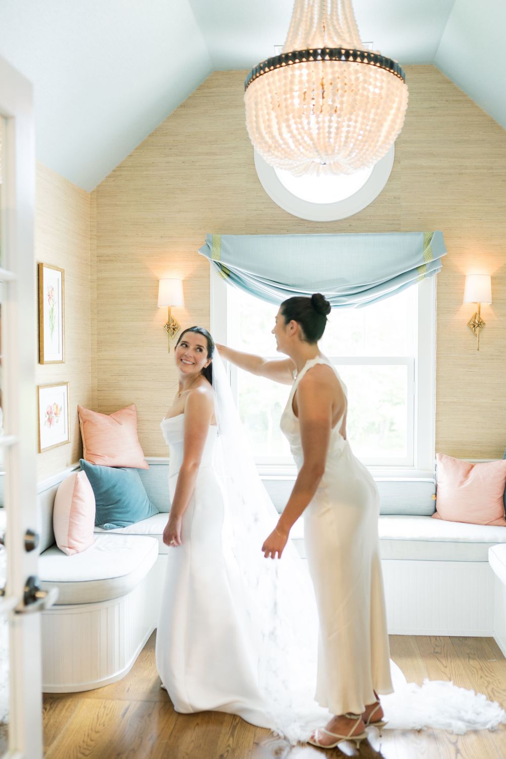 Elegant bridal suite with crystal chandelier and built-in window seating in soft colors.