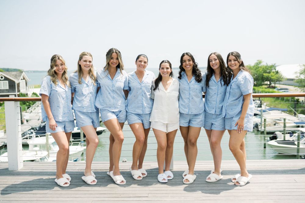 Group wearing coordinated blue outfits posing on waterfront deck.