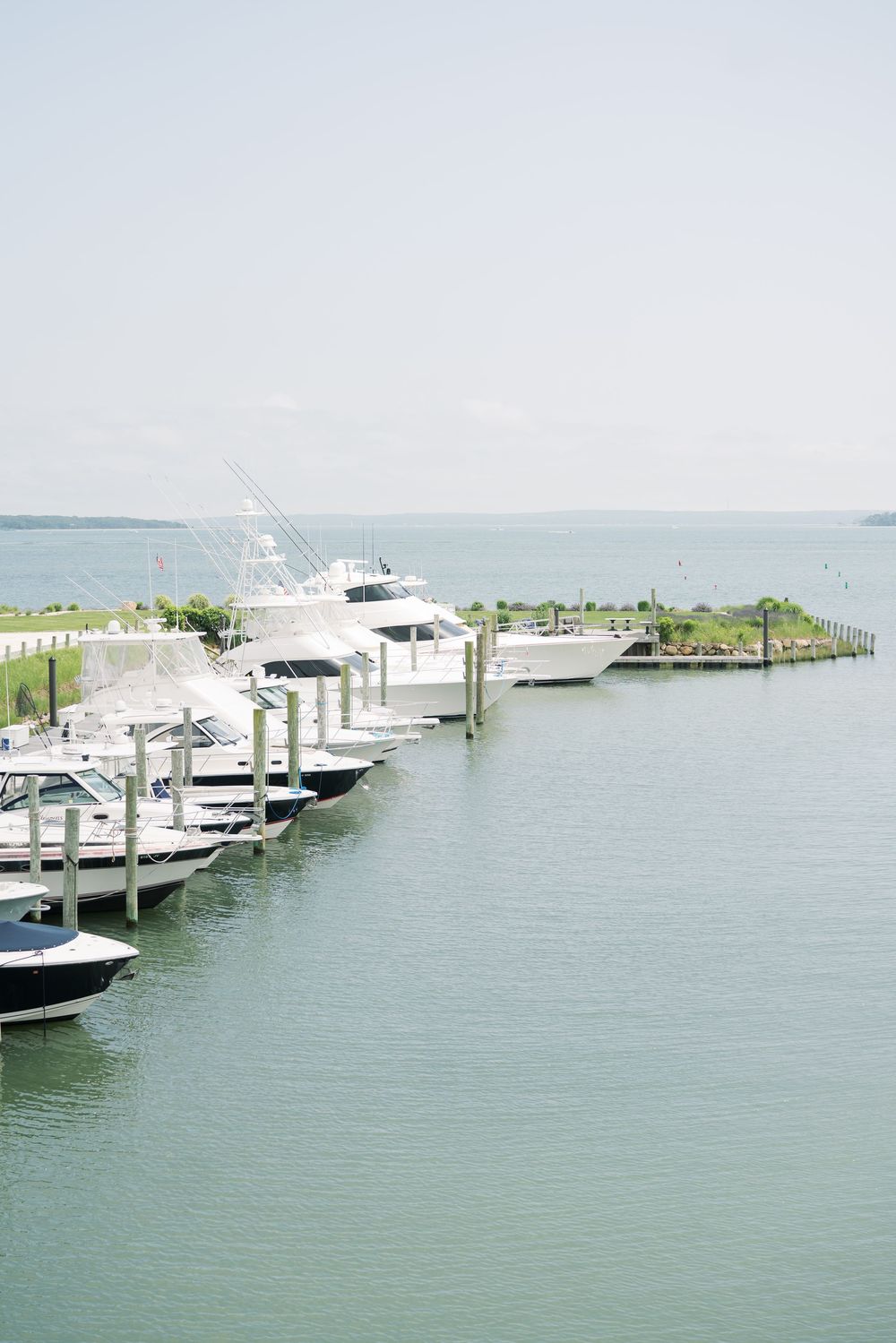 Marina with luxury boats docked along wooden pier on calm waters.