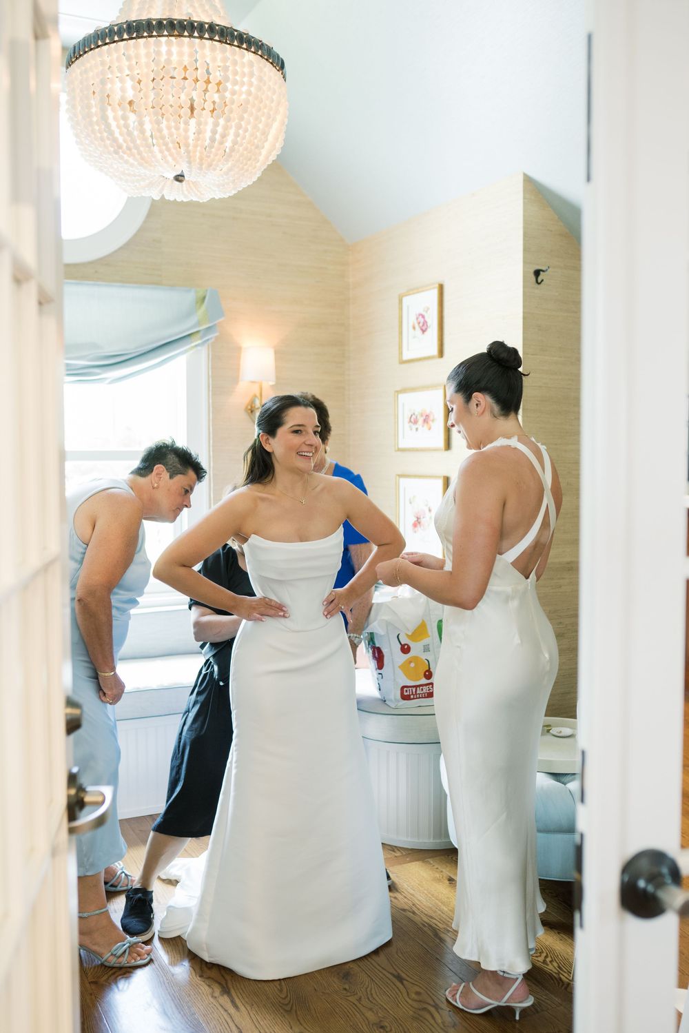Wedding preparations in elegant room with crystal chandelier and window seating.
