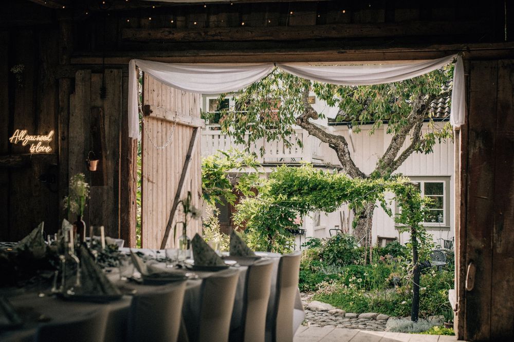 A rustic barn wedding venue decorated with elegant white drapes and floral arrangements creates a romantic atmosphere.