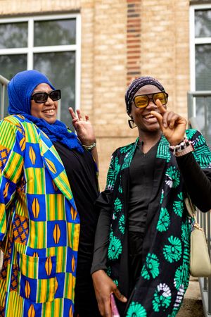 People wearing colorful African prints and traditional clothing dancing together at a cultural celebration.
