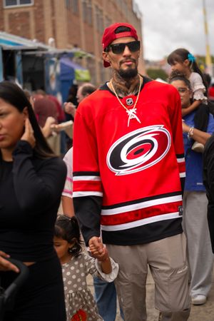 Sports fans wearing red Carolina Hurricanes jerseys gather at an outdoor event.