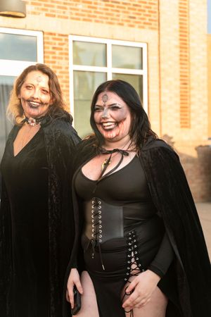 People wearing black outfits posing together outside a brick building.