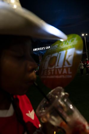 Blurred festival sign visible at night with America's Can text partially visible.