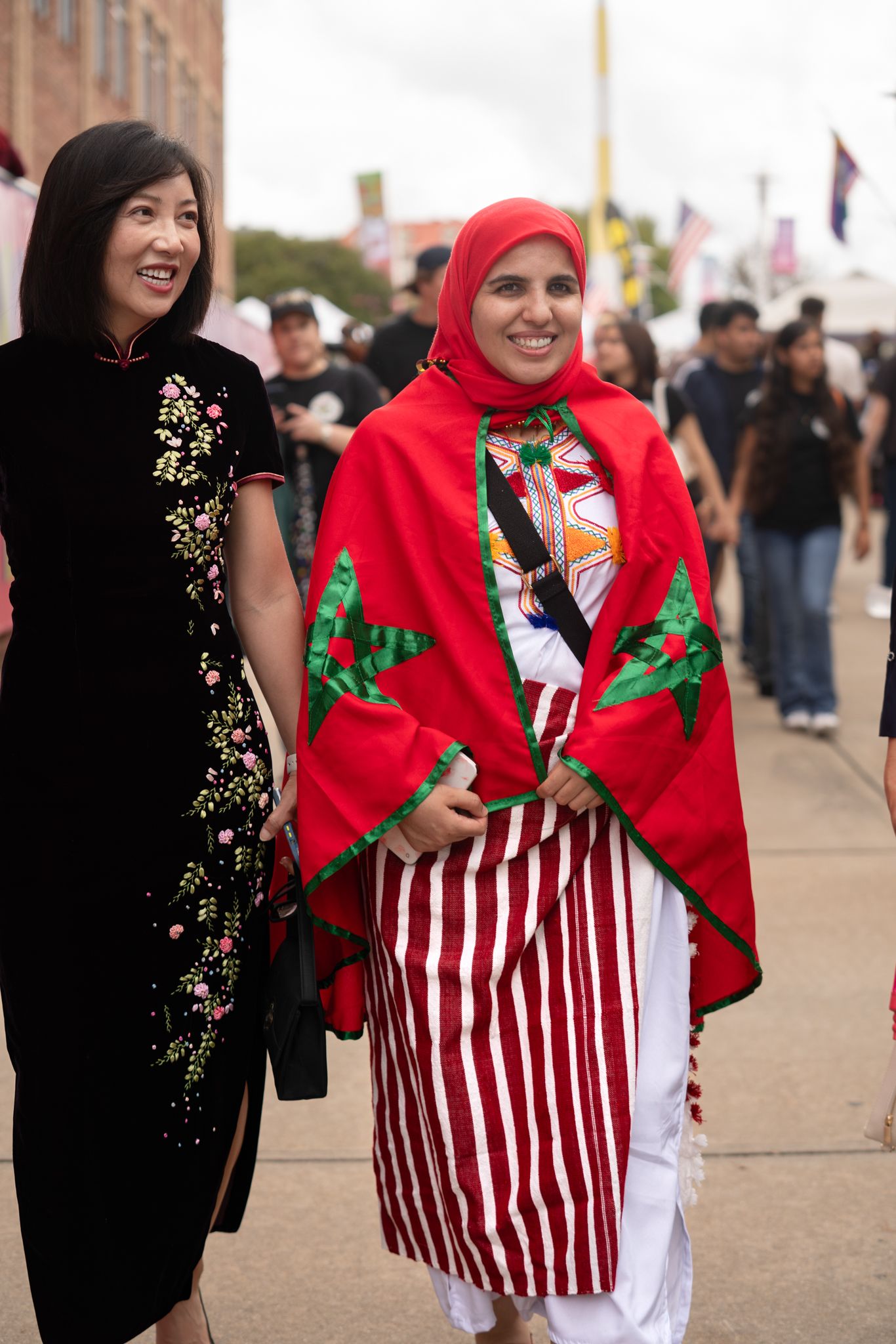People wearing festive red and white striped outfits with red scarves walk together at an outdoor event.