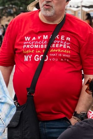 A group of people wearing matching red t-shirts with religious text that reads 'Waymaker' and 'Promise Keeper'.