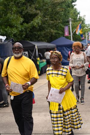 People wearing coordinated yellow and black checkered outfits at an outdoor festival event.