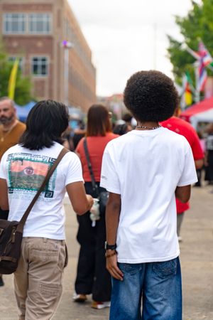 A group of people in white t-shirts and khaki pants walk together at an outdoor gathering.