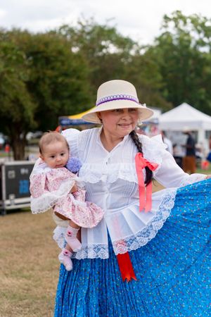 Traditional dancers in flowing blue and white dresses perform at an outdoor cultural festival.