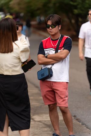 People in casual summer attire walking along a paved path at an outdoor gathering.