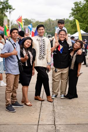 A group of friends in casual attire posing playfully at an outdoor event.