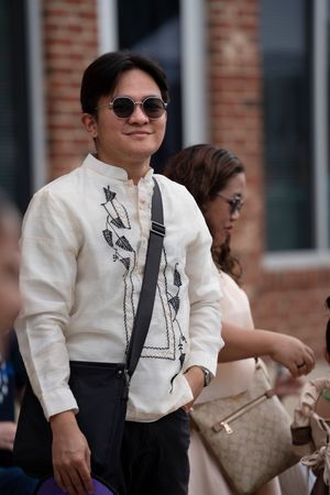Person in white printed shirt and dark pants at outdoor gathering.