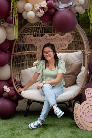 Decorative seating area with hanging balloons in burgundy and white tones creates an elegant photo backdrop.
