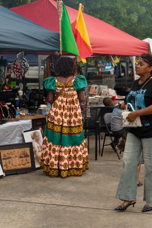 Women in traditional African print skirts walking through an outdoor market with colorful tents.