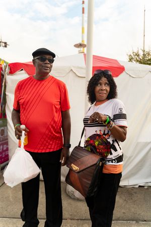 People in red shirts and casual wear walking through an outdoor festival.