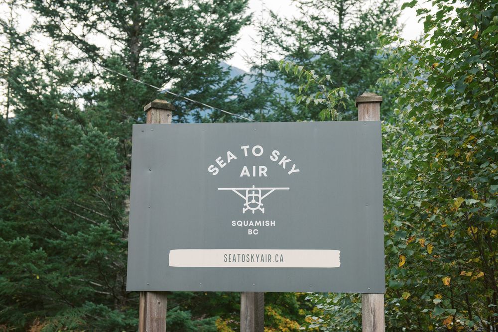 A series of gray wooden trail signs mounted on posts in a wooded forest setting.
