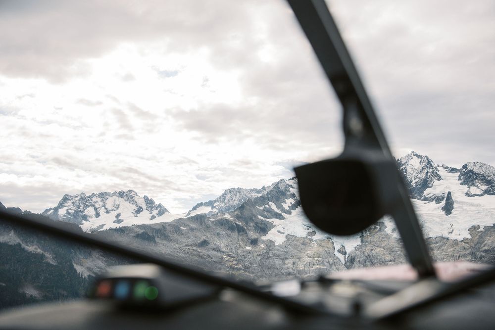 Snow-covered mountain peaks viewed through aircraft window during flight.