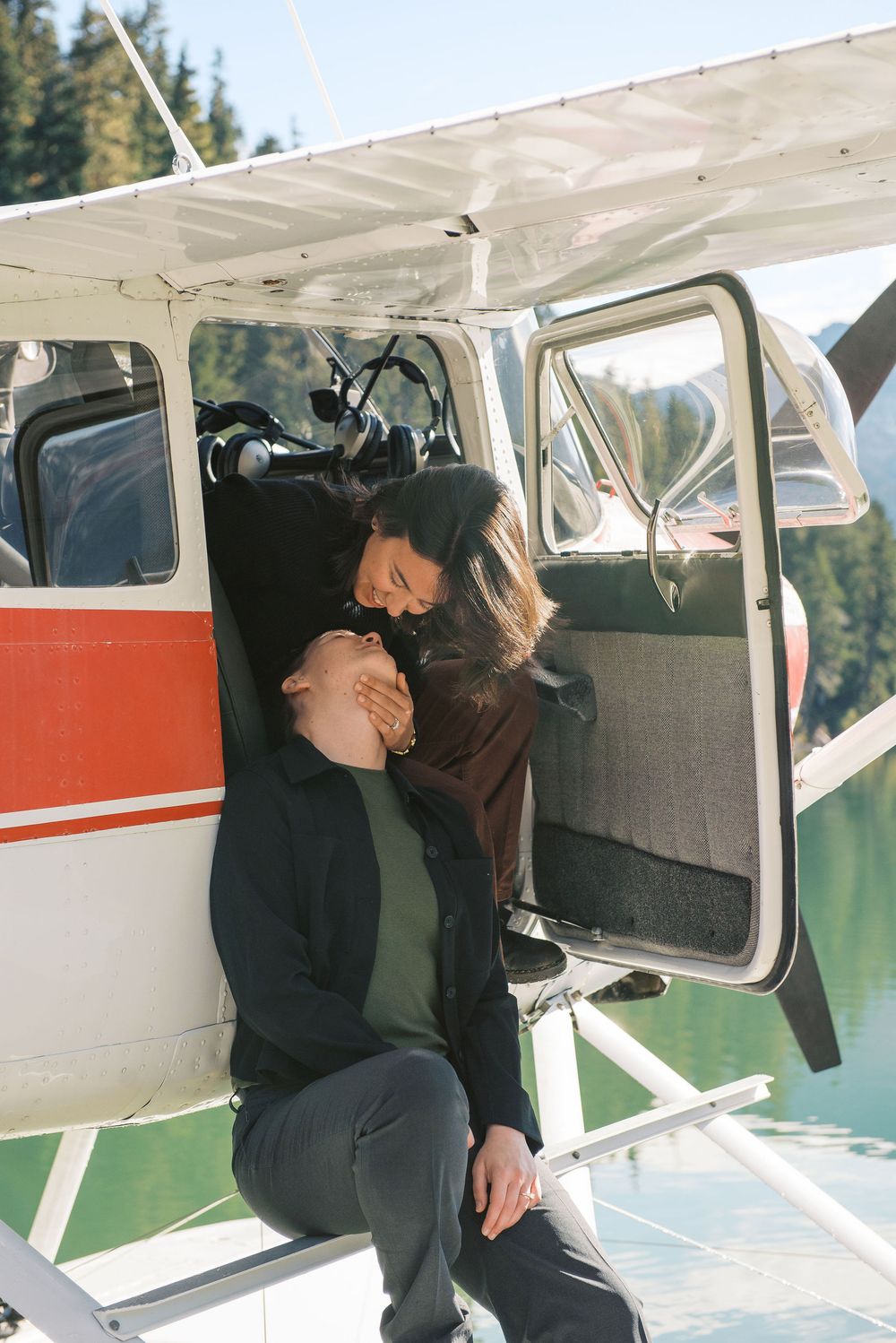 People boarding a small seaplane on a dock with scenic mountain lake views in the background.