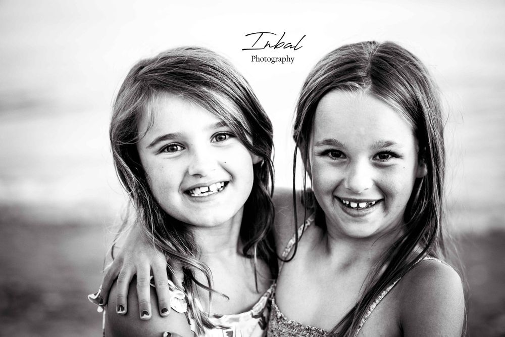 Black-and-white photo of the upper bodies of young girl cousins hugging each other.