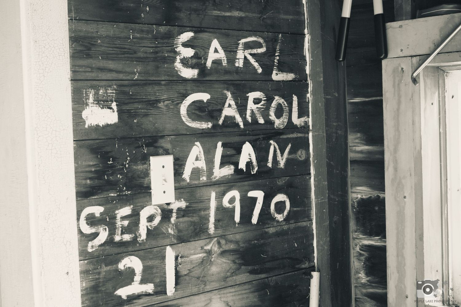 Vintage graffiti writing on wooden wall showing 'Earl Carol Alan Sept 1970'.