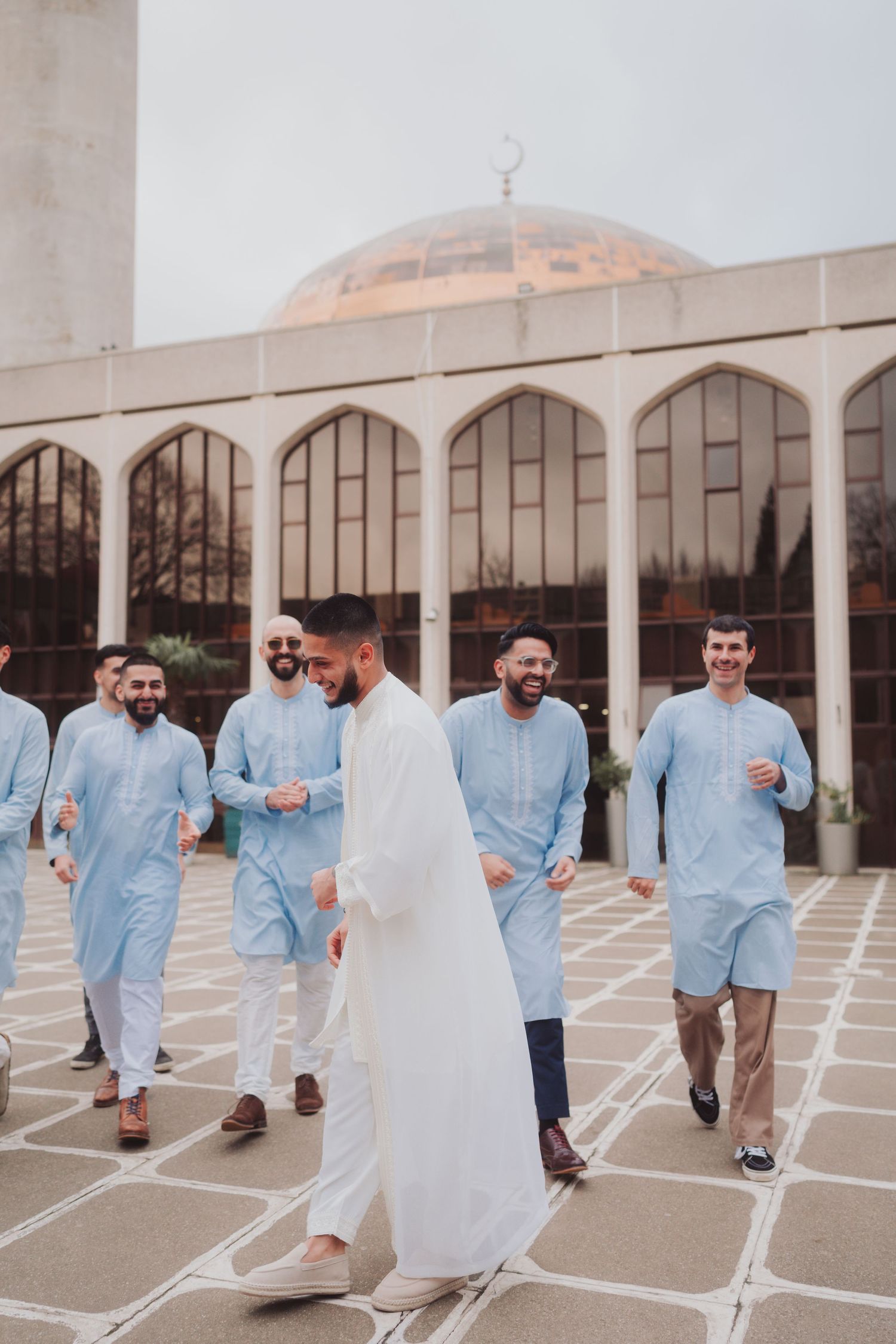 Group walking outside mosque in matching light blue traditional attire.