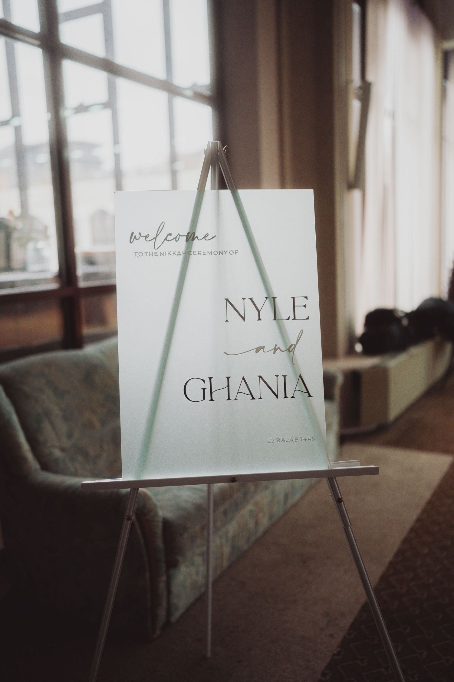 Wedding welcome sign on easel displays names Nyle and Ghania in elegant typography.