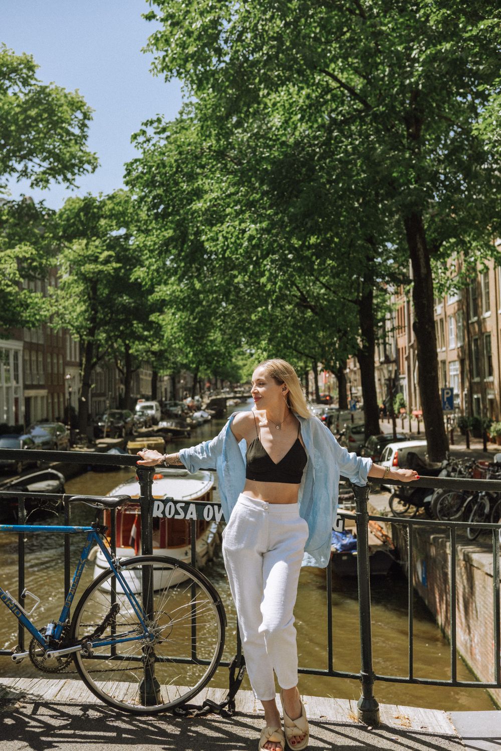 Sunny day along Amsterdam's canals with bicycles parked near historic buildings and trees.