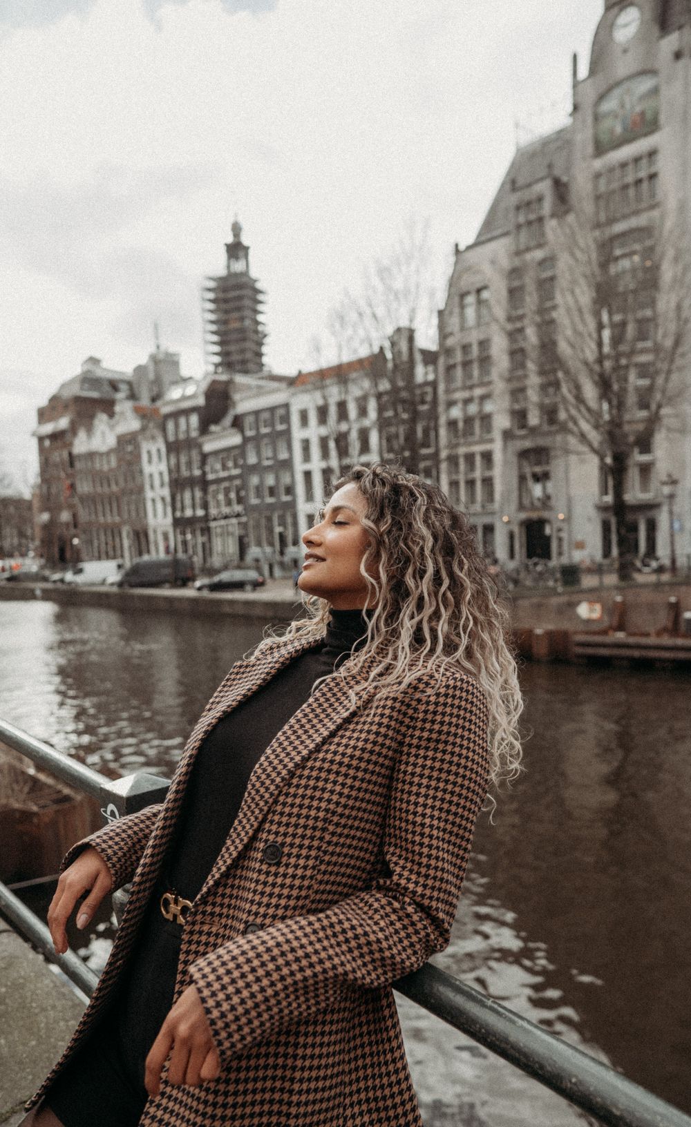 Moody urban landscape of Amsterdam's historic canal houses and waterways on an overcast day.