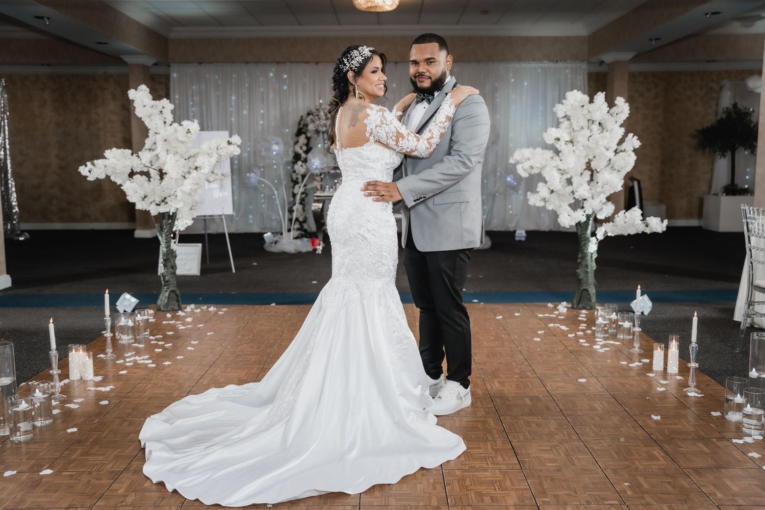 Elegant wedding ceremony setup with tall white floral arrangements and candles decorating a romantic indoor venue.
