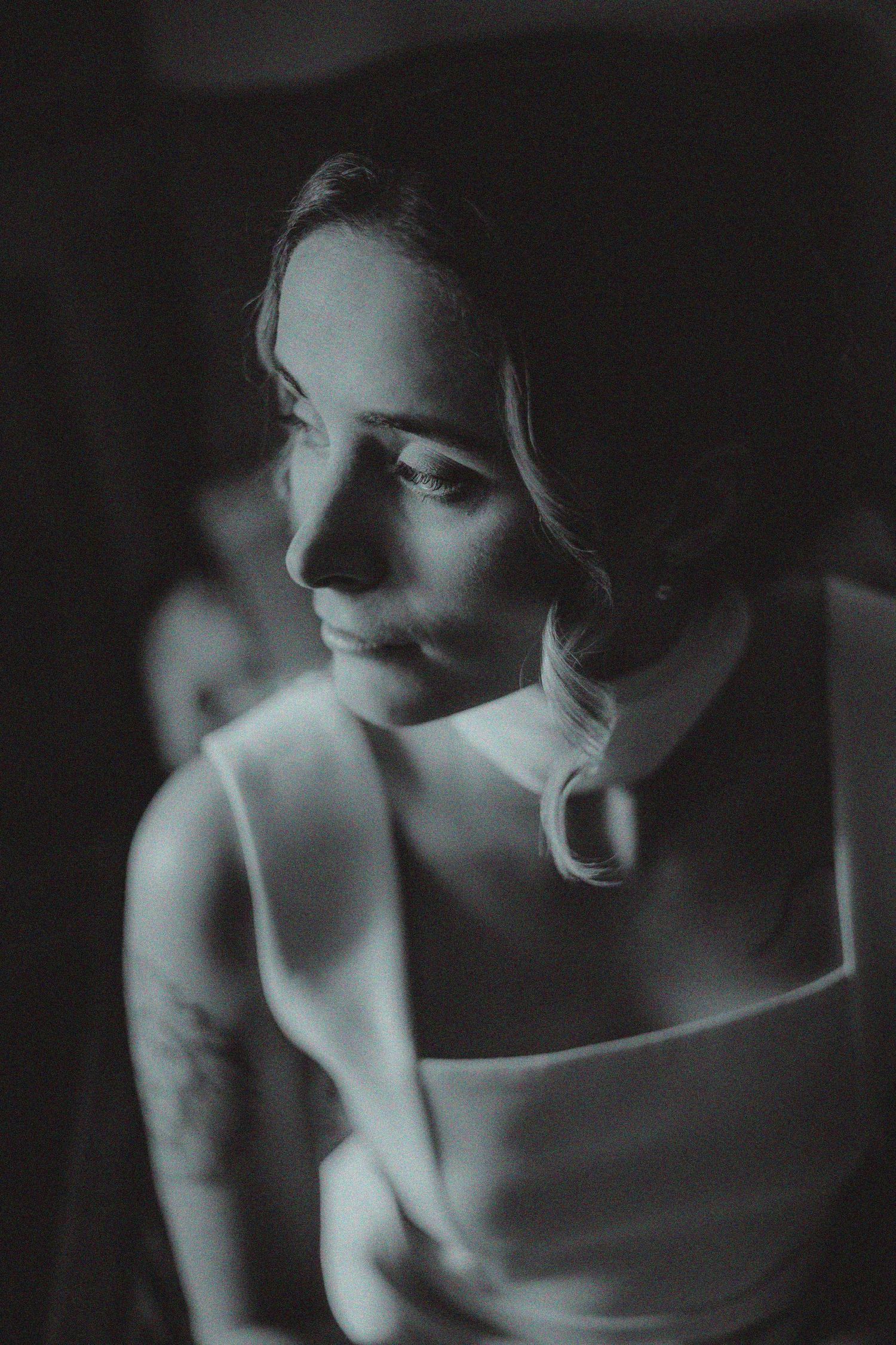 Artistic black and white portrait showing soft shadows and highlights on bare shoulders.