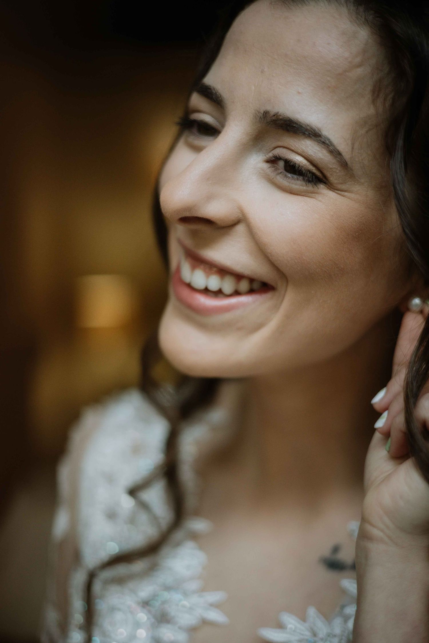 Close-up portrait showing delicate lace details and pearl earrings in warm lighting.