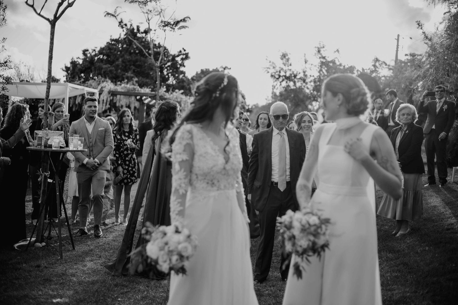 Wedding guests gather outdoors in black and white as they celebrate the newlyweds.