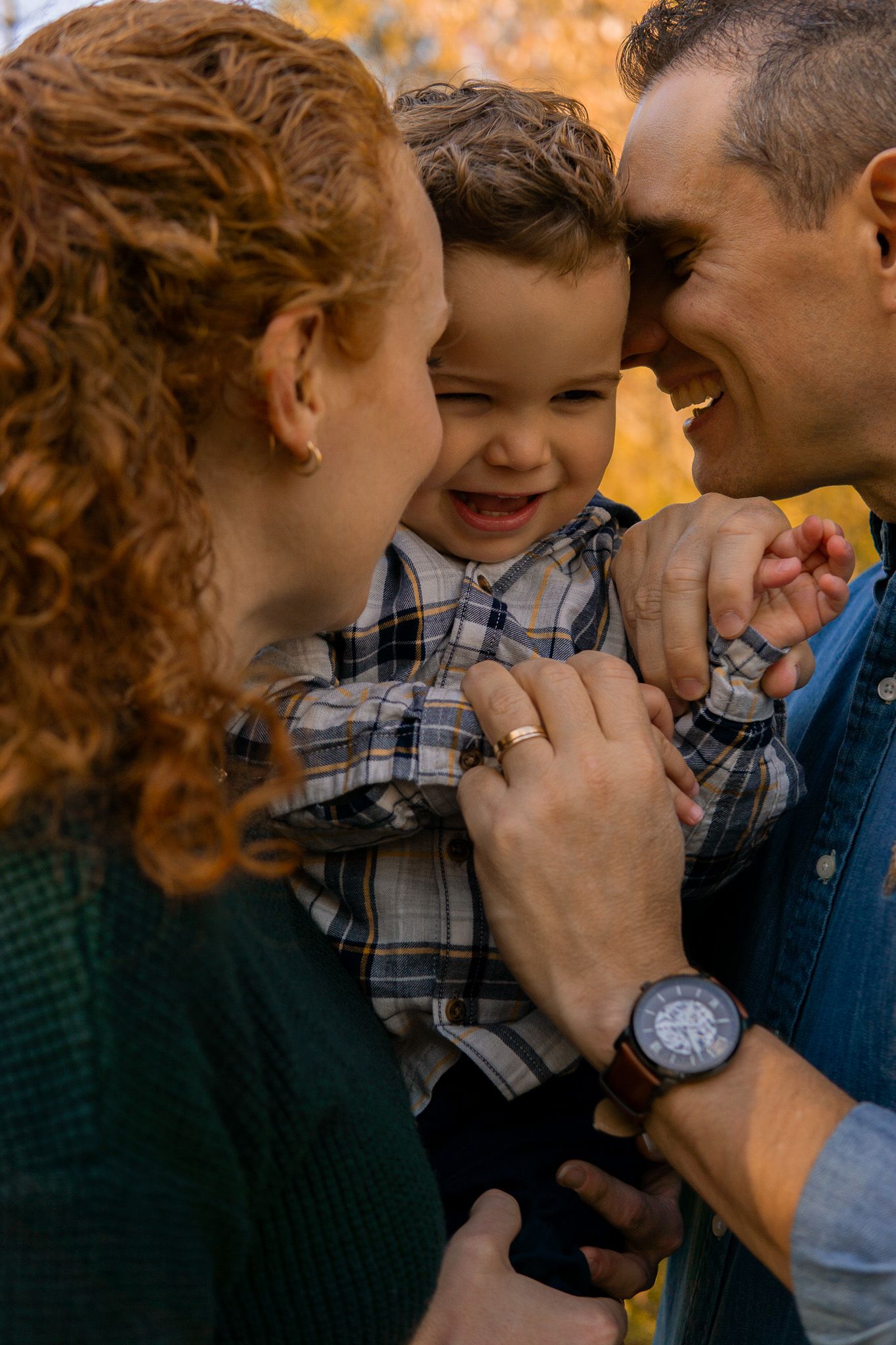 Dad and mom holding the baby and smiling in a fall day