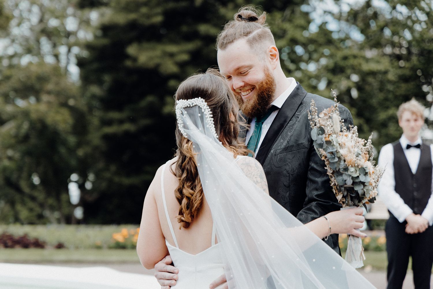 A sweet moment between a couple during their First Look with a veil flowing in the breeze, captured by Apertured Media Auckland Wedding Phot
