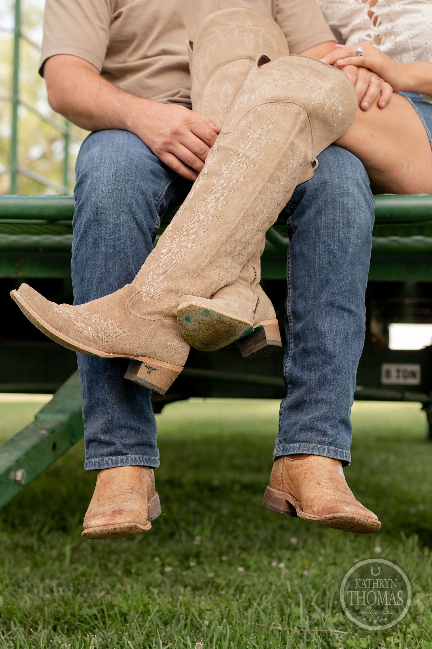 Close-up of couple's boots and legs sitting together on green metal bleachers.