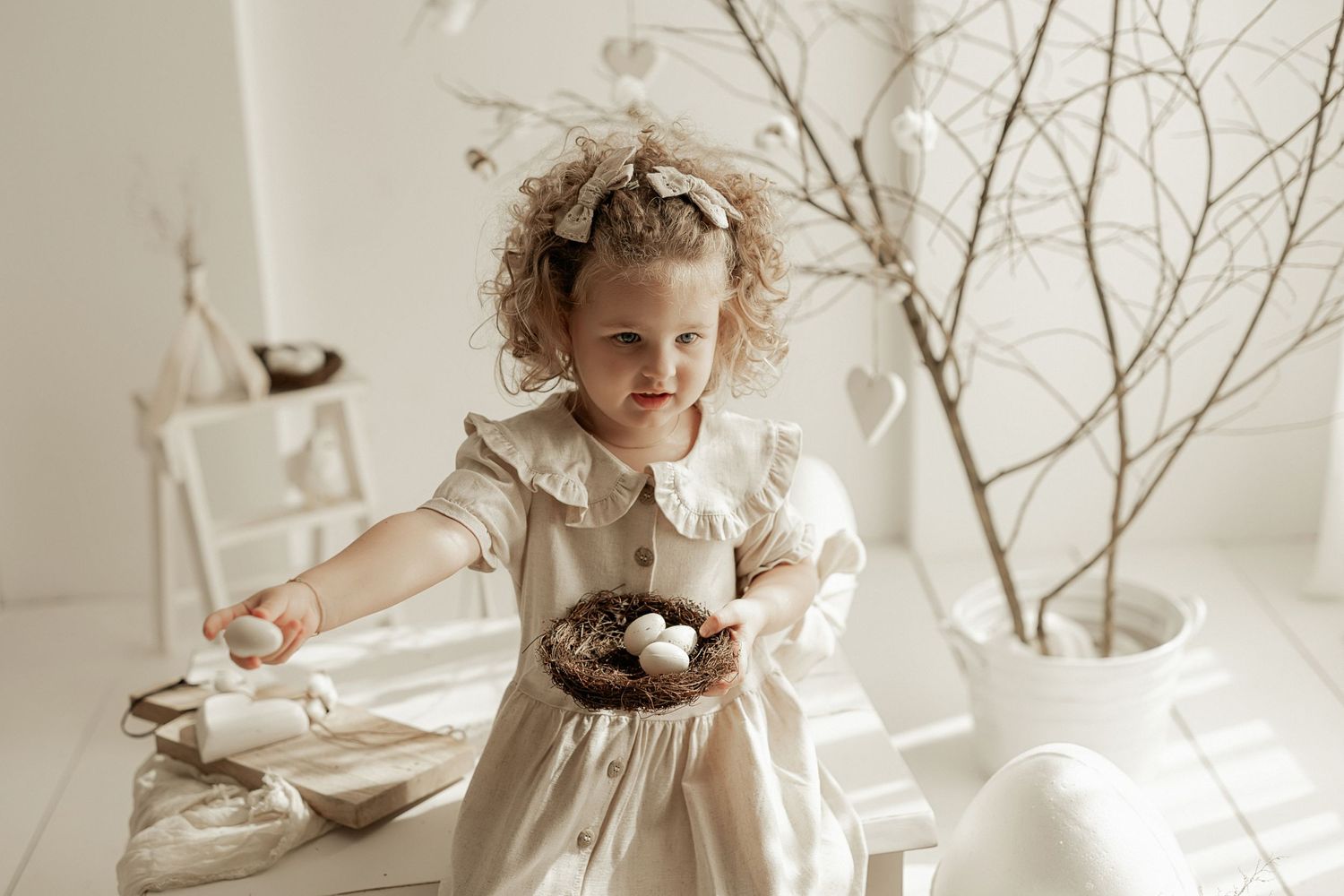 A whimsical scene with a curly-haired child in a vintage dress playing at a table decorated with dried branches.