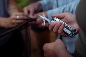 Close-up of hands holding and examining a multi-tool or pocket knife with scissors extended.
