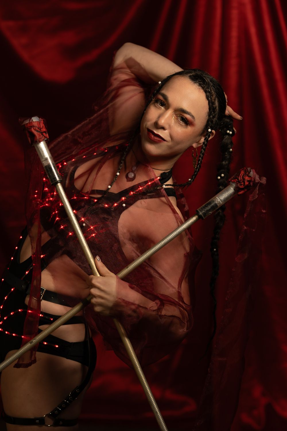 Fine Art Fotografie. Theatrical performance shot with crossed batons against dramatic red curtain background.