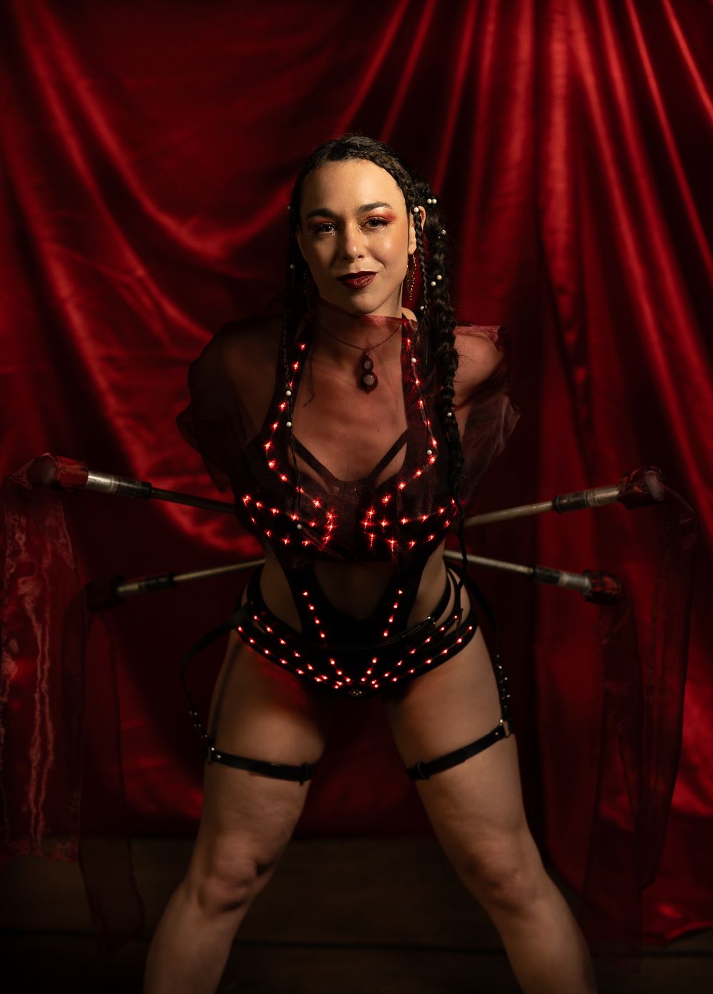 Fine Art Portrait. Performer in red LED-lit costume poses dramatically against red velvet backdrop.