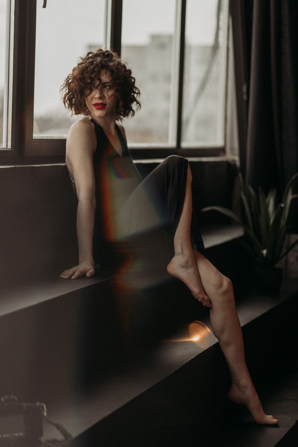 Moody boudoir photo by window with dramatic natural lighting.