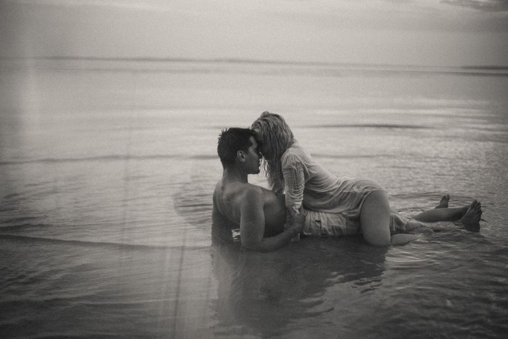Romantic couple portrait series in shallow ocean water at sunset.