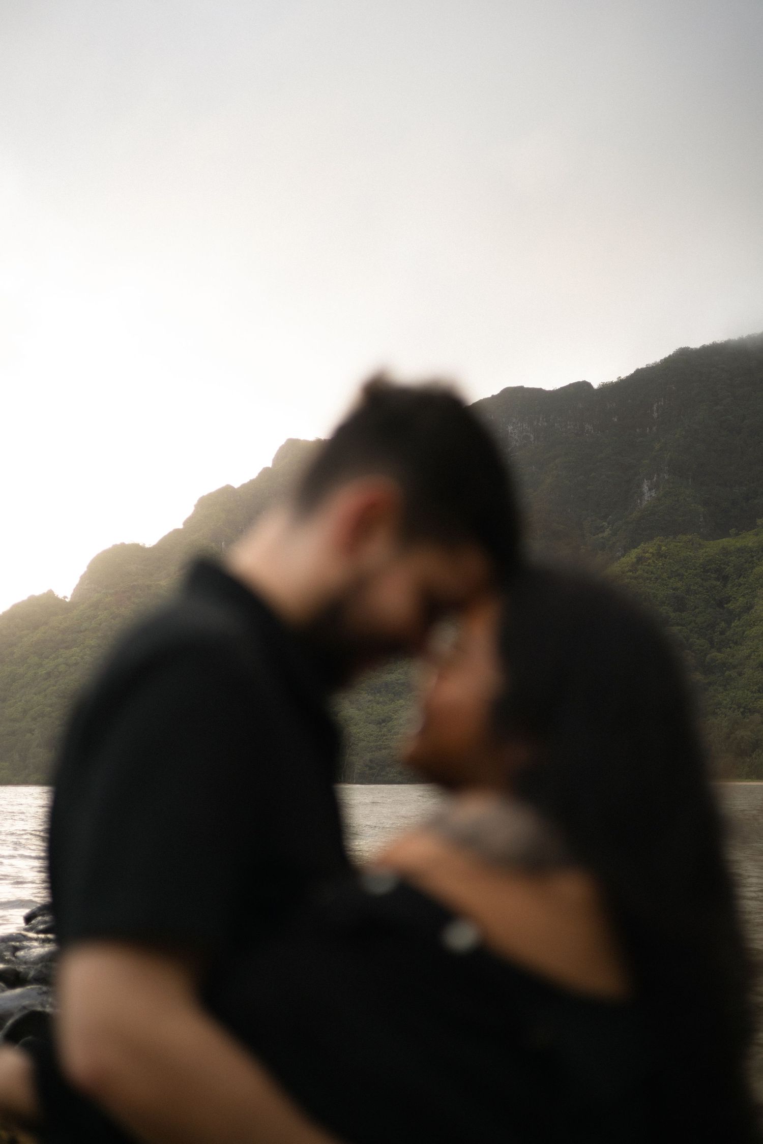 A silhouetted couple sharing an intimate moment against a mountain landscape at sunset.