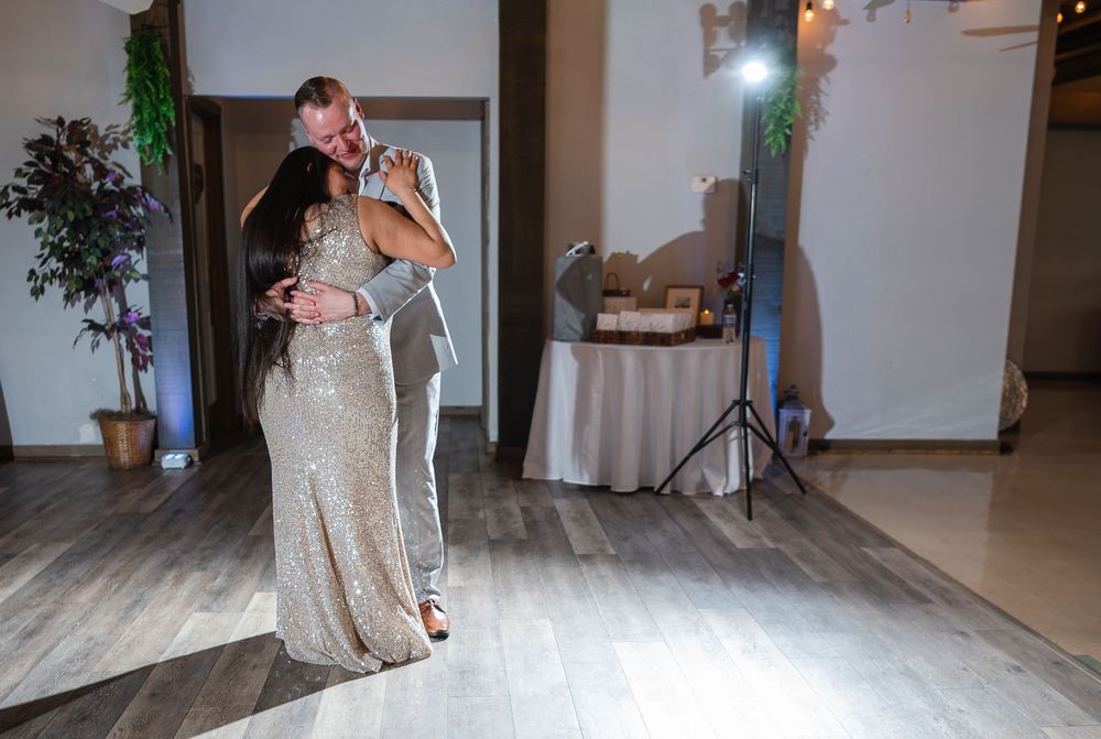 Couple sharing a romantic first dance at their wedding reception in an elegant venue with warm lighting.