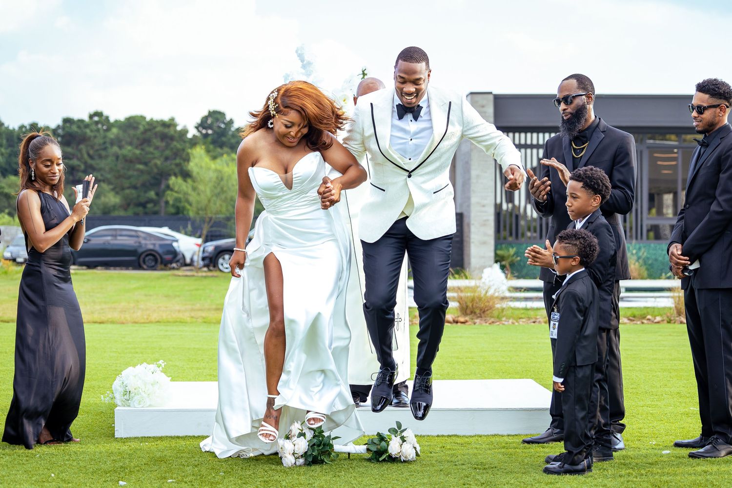 Couple in formal attire celebrate on outdoor stage as guests cheer.