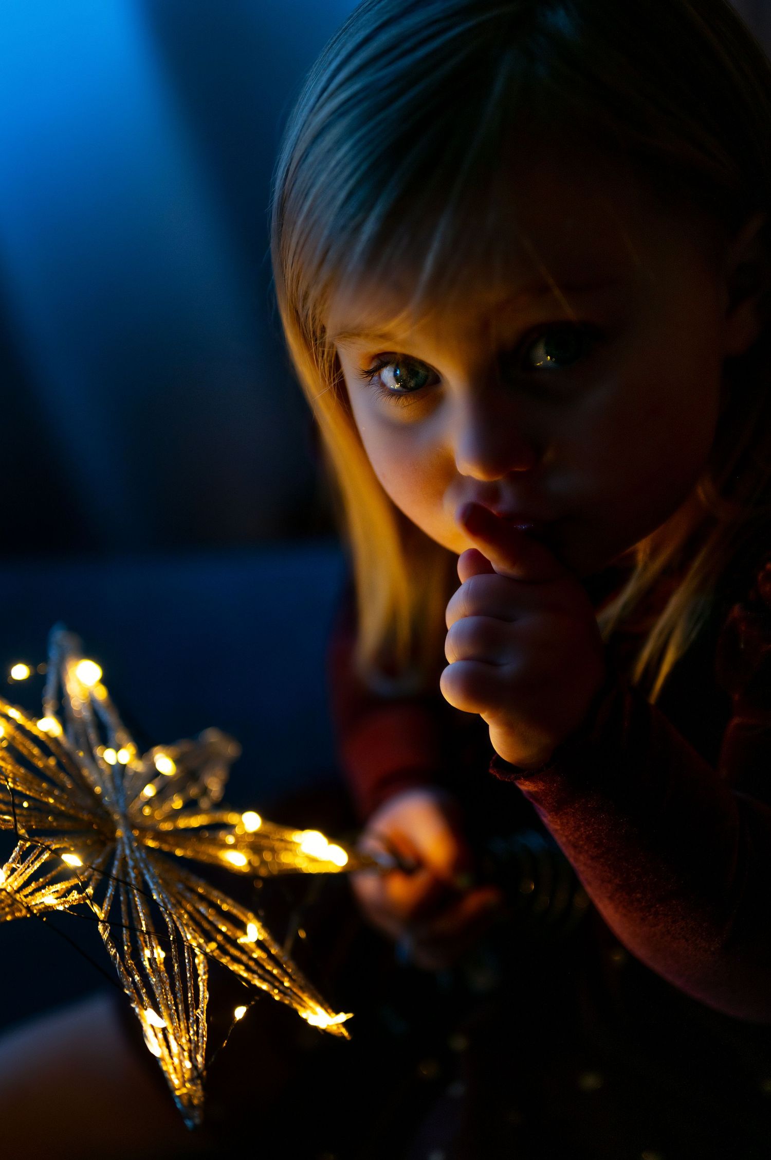 Close-up portrait with golden Christmas lights creating magical bokeh effect.