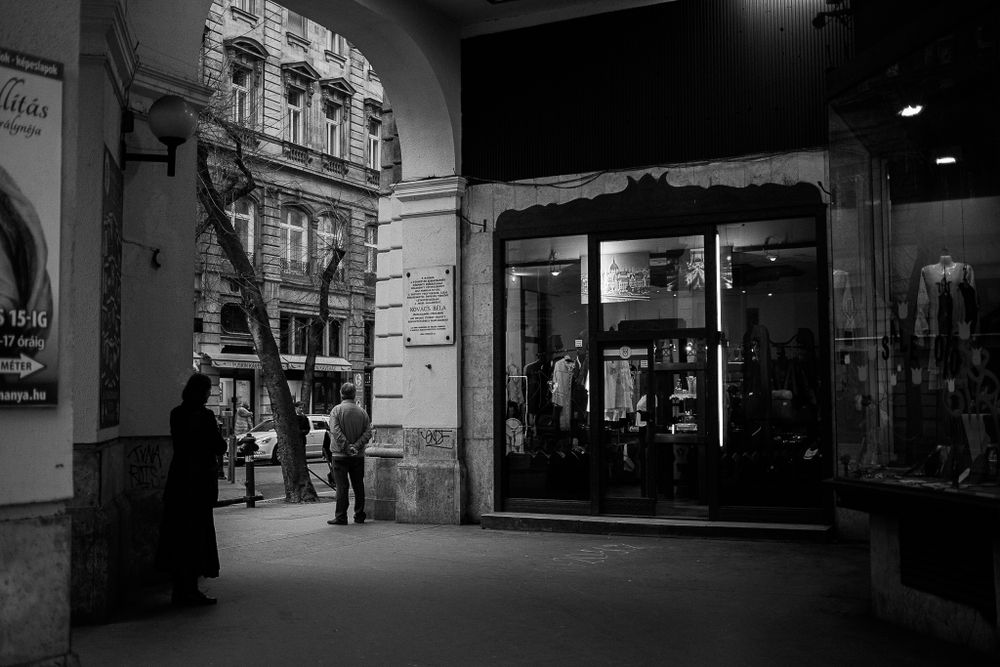 Black and white view of a classic European storefront with arched architecture.