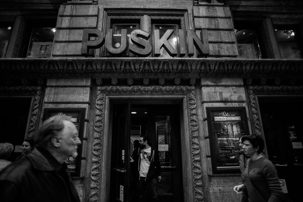Urban storefront with 'Puskin' signage above entrance in classical architectural setting.