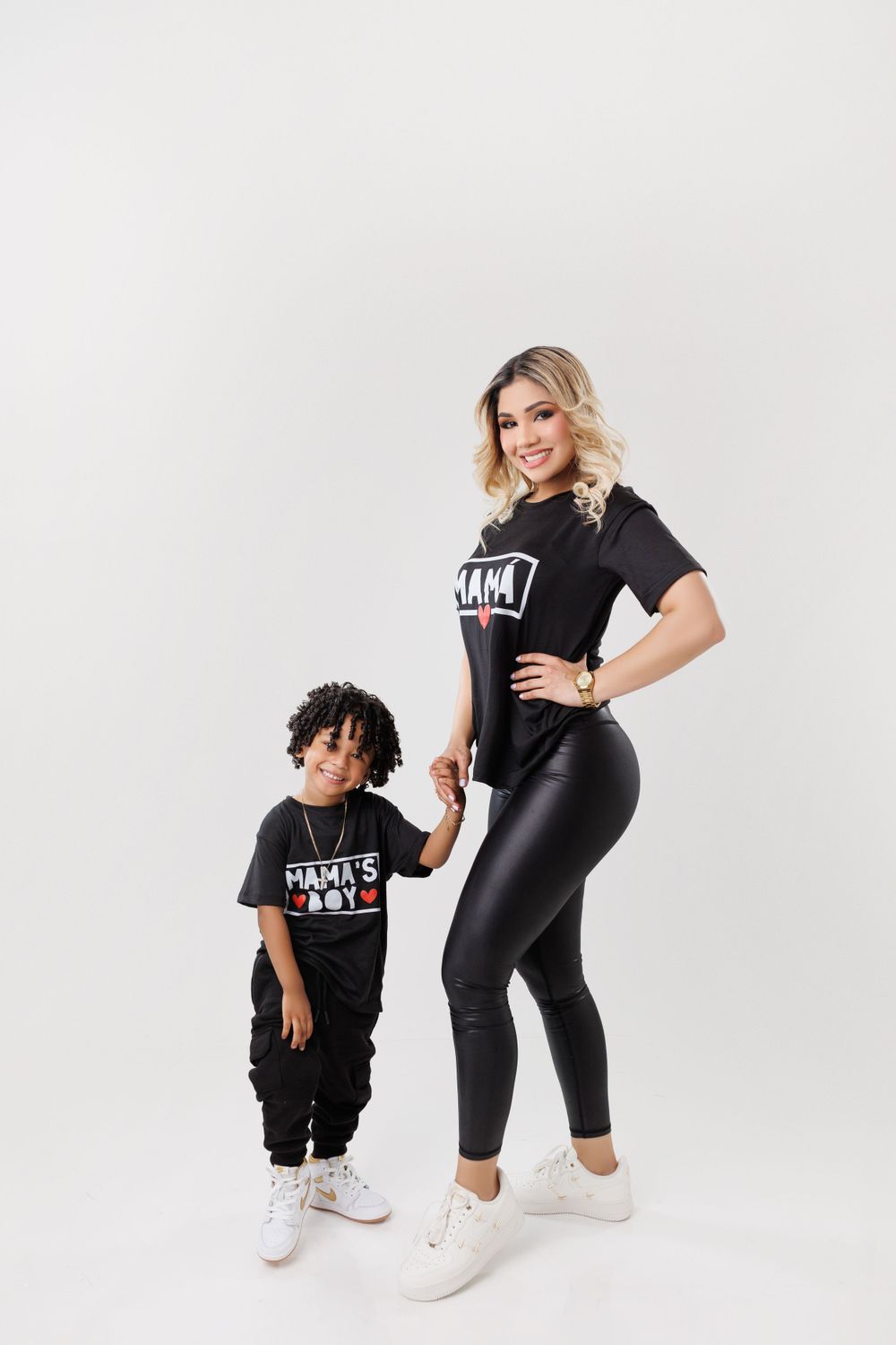 Mother and child wearing matching black outfits pose together in a studio setting.