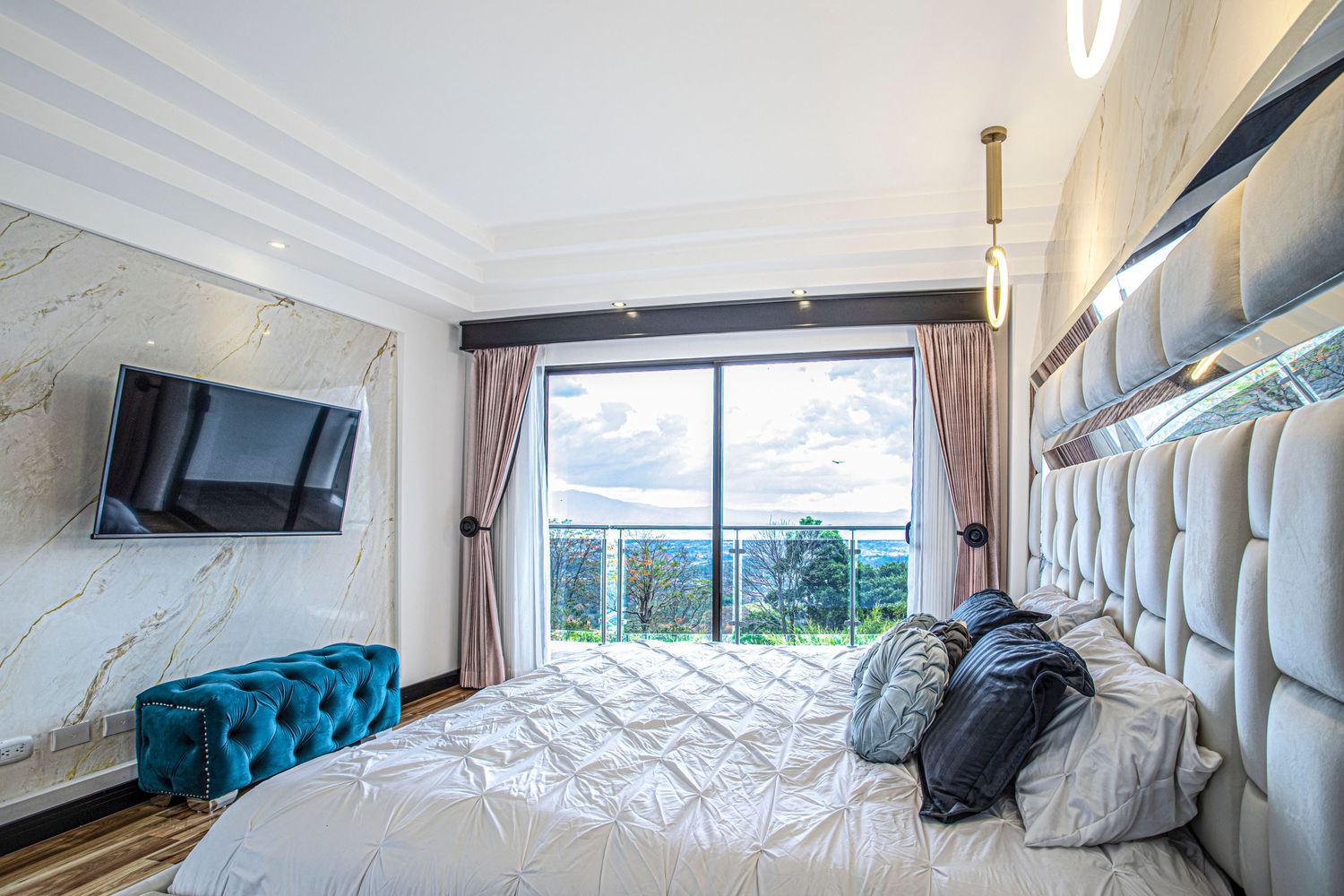 Bright and spacious master bedroom with large windows, a flat-screen TV, and a sophisticated design for relaxation